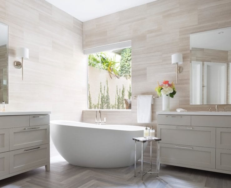 This master bathroom by Krista + Home features sconces by Kallista and hardware from Waterworks. Tile laid in a herringbone pattern is one of Watterworth Alterman’s favorite applications to make the flooring pop.