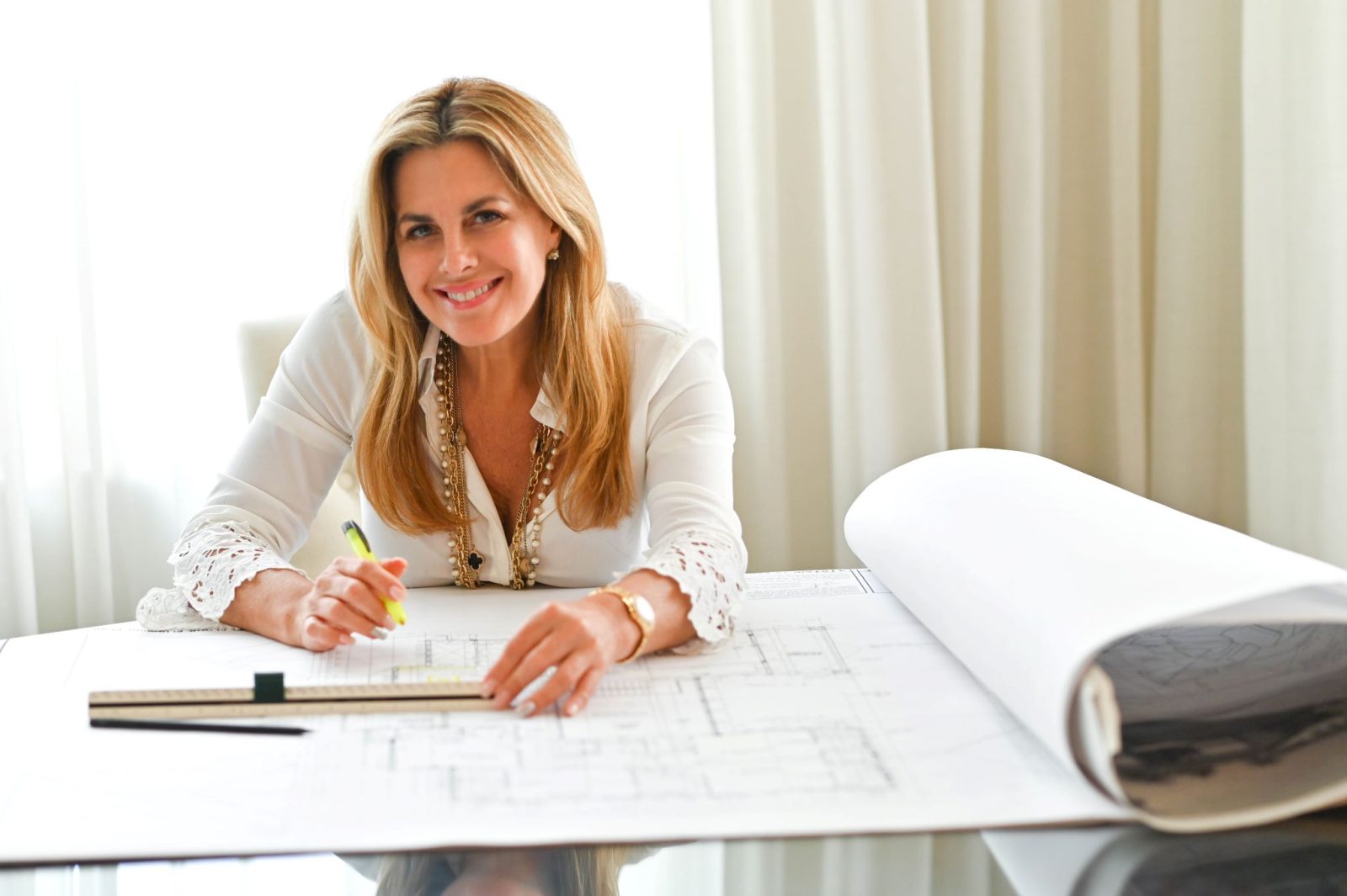 Maura Rossi, an accomplished interior designer, standing in a stylishly decorated living room she designed, exemplifying her elegant and innovative aesthetic.