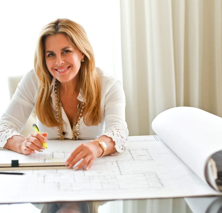 Maura Rossi, an accomplished interior designer, standing in a stylishly decorated living room she designed, exemplifying her elegant and innovative aesthetic.