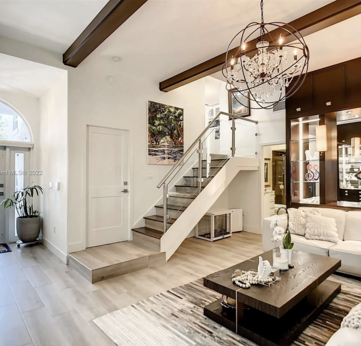 Maura Rossi, an accomplished interior designer, standing in a stylishly decorated living room she designed, exemplifying her elegant and innovative aesthetic.