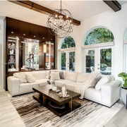 Maura Rossi, an accomplished interior designer, standing in a stylishly decorated living room she designed, exemplifying her elegant and innovative aesthetic.