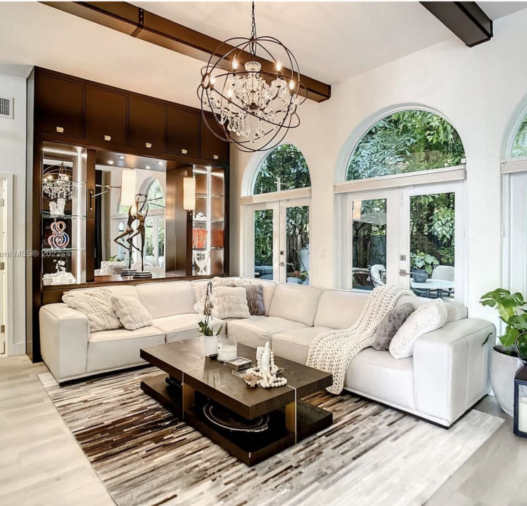 Maura Rossi, an accomplished interior designer, standing in a stylishly decorated living room she designed, exemplifying her elegant and innovative aesthetic.