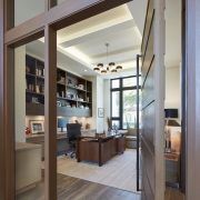 Gage Hartung, a professional and focused interior designer, reviewing blueprints and fabric samples in his well-organized office, surrounded by elegant and modern design elements.