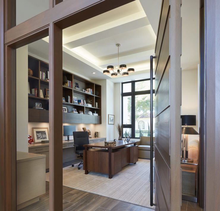 Gage Hartung, a professional and focused interior designer, reviewing blueprints and fabric samples in his well-organized office, surrounded by elegant and modern design elements.