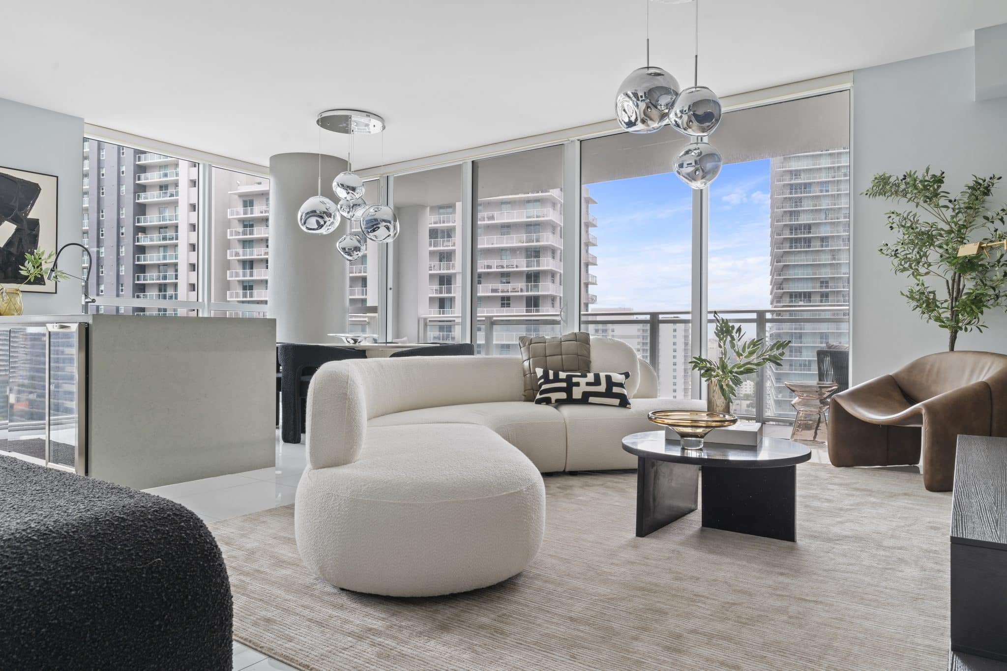 A sculptural white curved sofa softens bold high-rise architecture with warmth, texture, and contrast in this bachelor’s Miami residence.