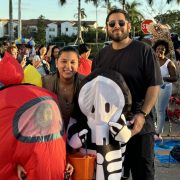 Families in creative costumes enjoying Miami Beach’s Halloween block party under the palm trees.