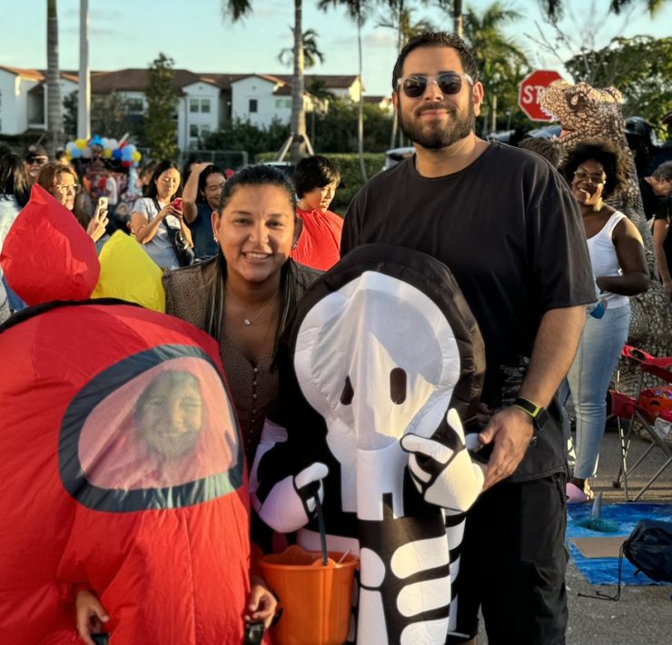 Families in creative costumes enjoying Miami Beach’s Halloween block party under the palm trees.
