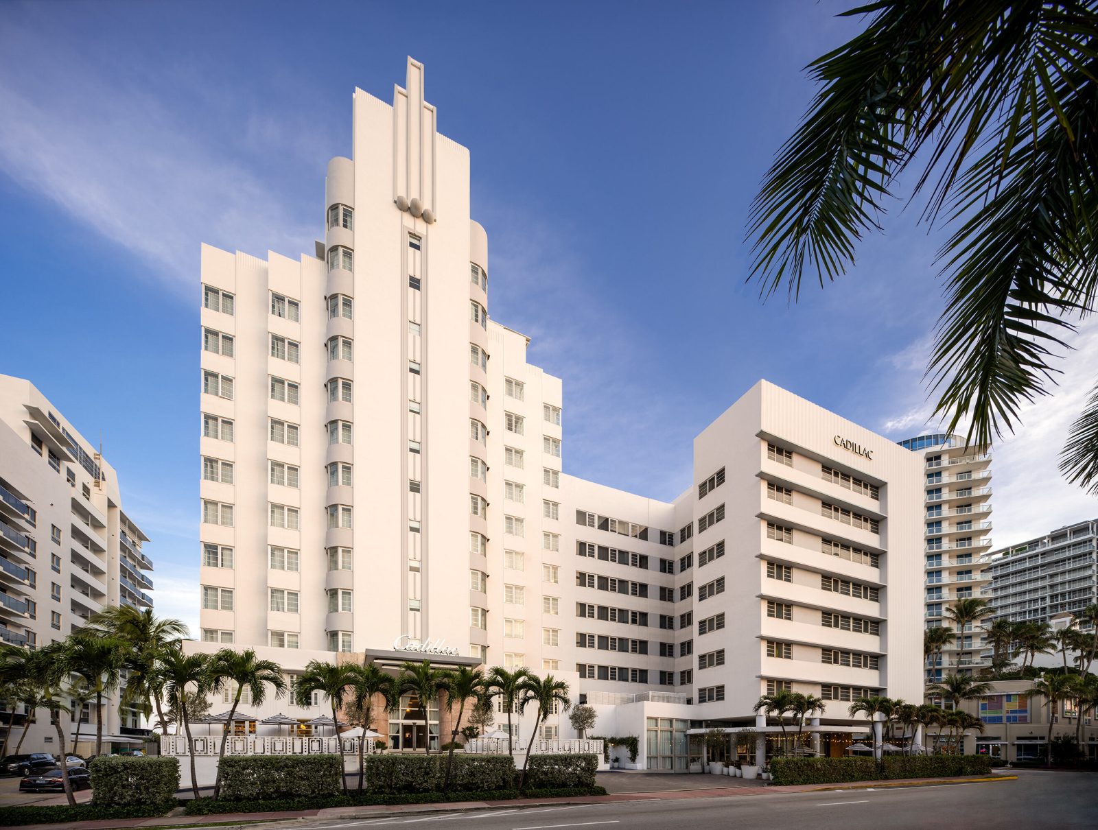 Iconic Art Deco-style luxury hotel in Miami Beach surrounded by palm trees and ocean views. Caption: Miami Beach’s timeless Art Deco charm — a blend of heritage architecture and modern sophistication.