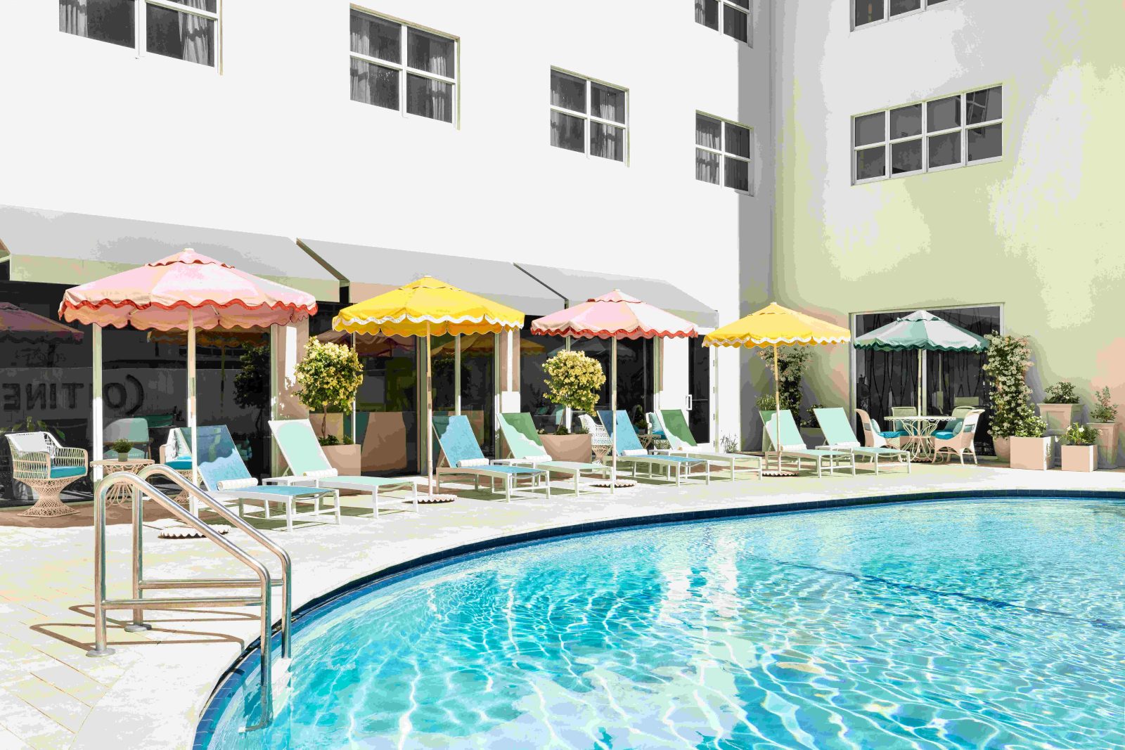 Retro-inspired pool area at The Catalina Hotel featuring pastel umbrellas and sun loungers. Caption: Playful colors and vintage flair define The Catalina Hotel’s iconic Miami Beach poolside experience.