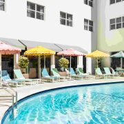 Retro-inspired pool area at The Catalina Hotel featuring pastel umbrellas and sun loungers. Caption: Playful colors and vintage flair define The Catalina Hotel’s iconic Miami Beach poolside experience.