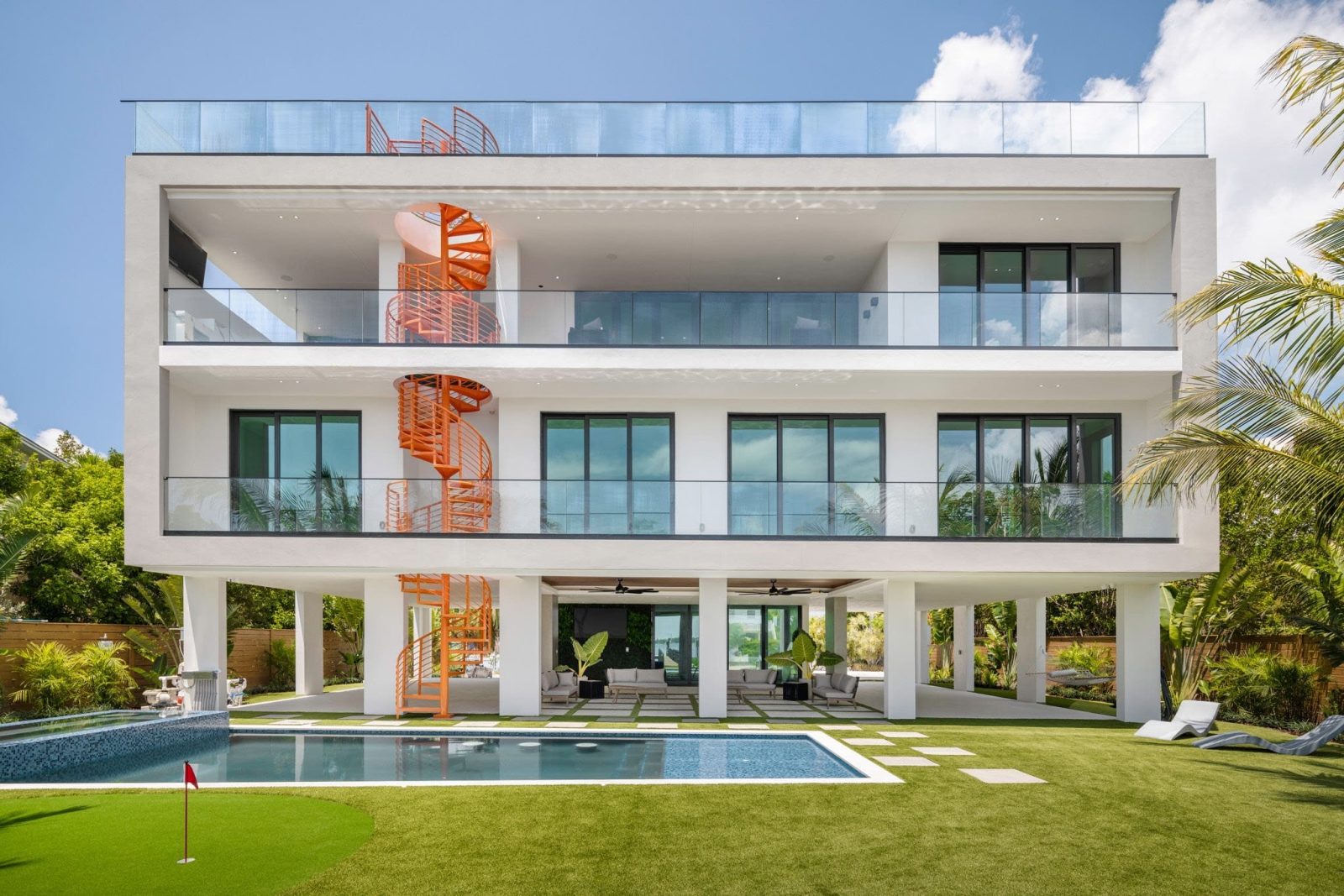 Exterior view of the $7.3M Key Largo villa showcasing its modern architecture, orange spiral staircase, pool, and rooftop terrace overlooking the bay.
