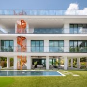 Exterior view of the $7.3M Key Largo villa showcasing its modern architecture, orange spiral staircase, pool, and rooftop terrace overlooking the bay.
