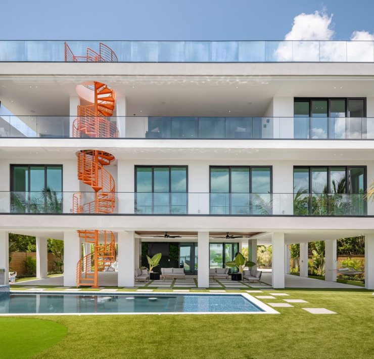 Exterior view of the $7.3M Key Largo villa showcasing its modern architecture, orange spiral staircase, pool, and rooftop terrace overlooking the bay.