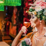 Woman in floral costume sipping a Halloween-themed cocktail at a Miami restaurant during spooky season.