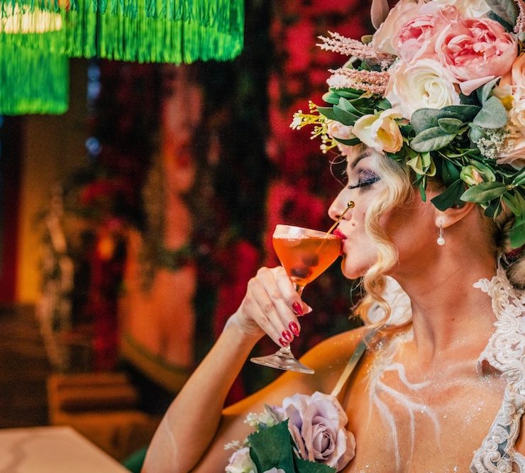Woman in floral costume sipping a Halloween-themed cocktail at a Miami restaurant during spooky season.