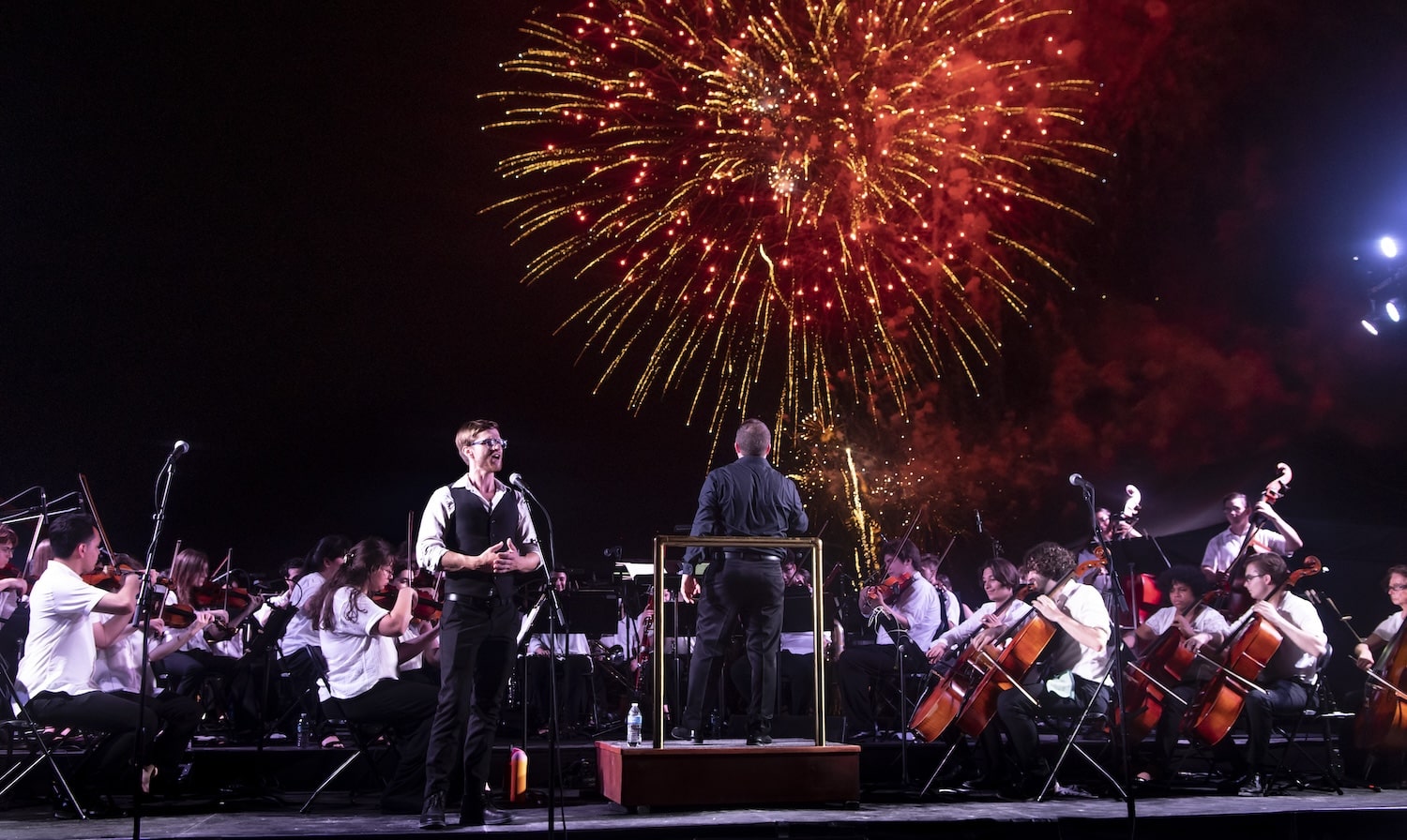 Outdoor symphony performance in Miami Beach with fireworks lighting up the sky during Fall for the Arts cultural season.