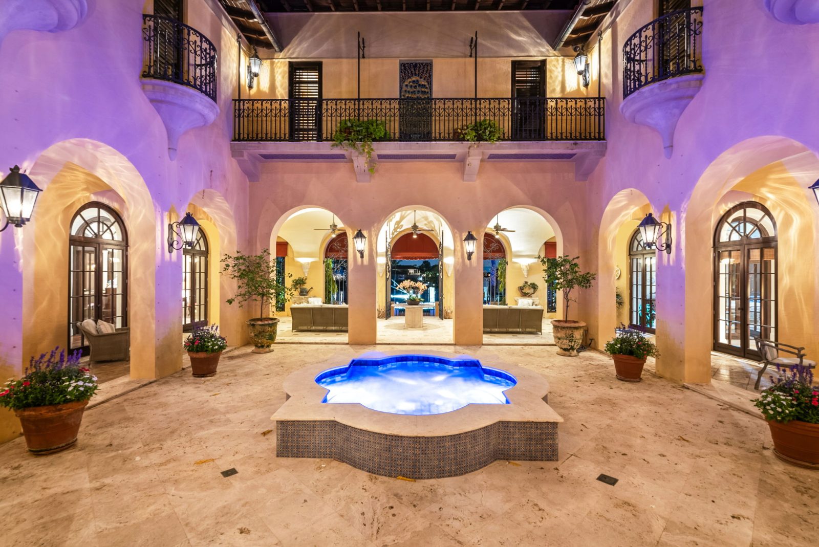 Illuminated courtyard with central fountain, arched balconies, and Mediterranean details inside Codina’s Coral Gables mansion.