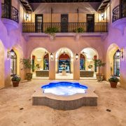 Illuminated courtyard with central fountain, arched balconies, and Mediterranean details inside Codina’s Coral Gables mansion.