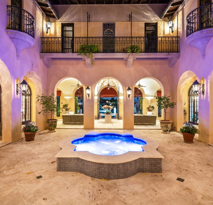 Illuminated courtyard with central fountain, arched balconies, and Mediterranean details inside Codina’s Coral Gables mansion.