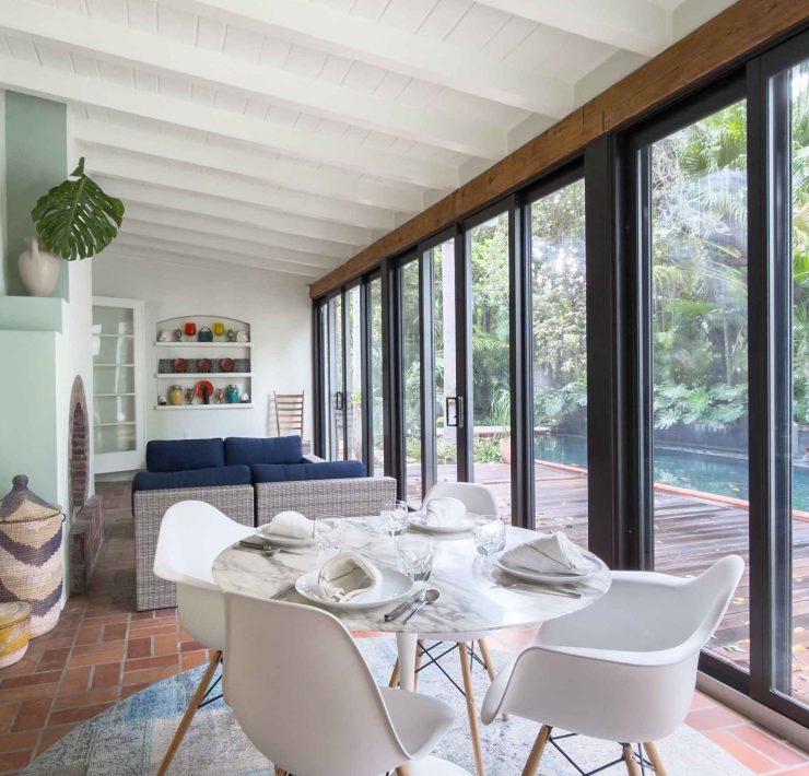 Dining area with floor-to-ceiling windows in the Victor Nellenbogen–designed tropical Deco home in Belle Meade, Miami.