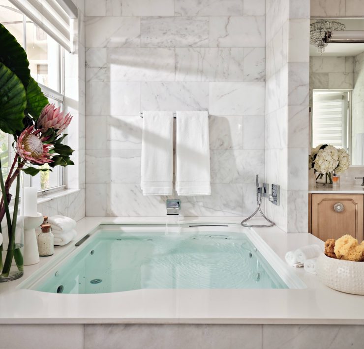 Ensuite bathroom with soaking tub, marble surfaces, and wood cabinetry designed by Maritza Capiro.