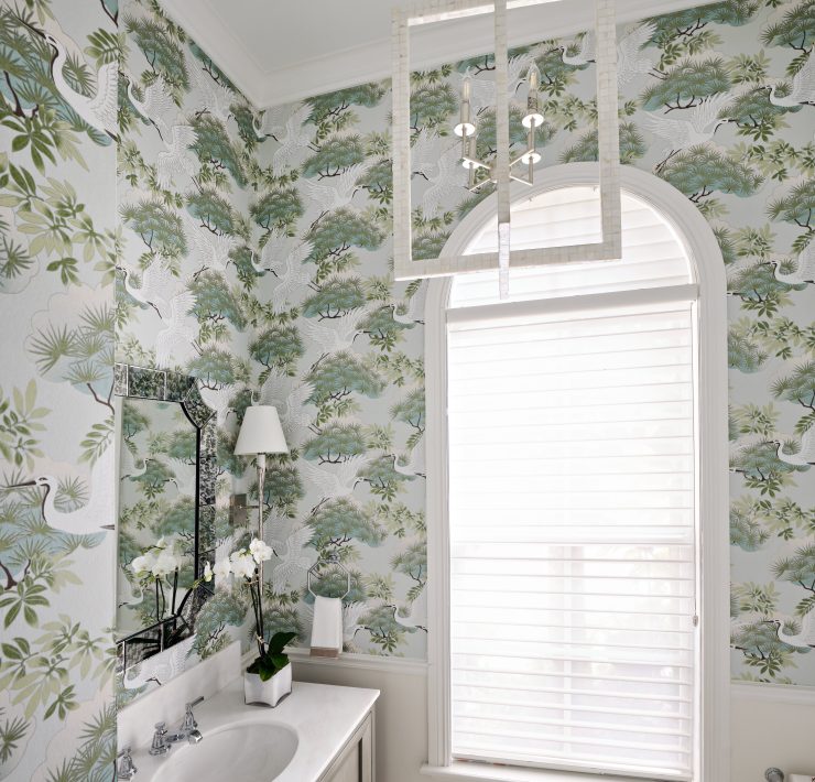 Powder room featuring botanical wallpaper, white vanity, and large arched window.