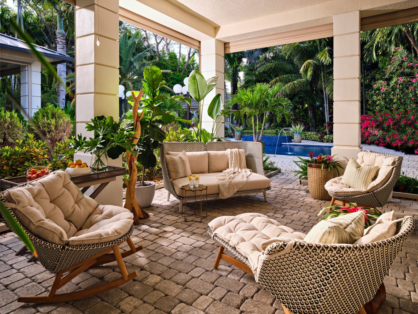 Covered patio with woven seating and tropical landscaping, designed for entertaining in Pinecrest Oasis