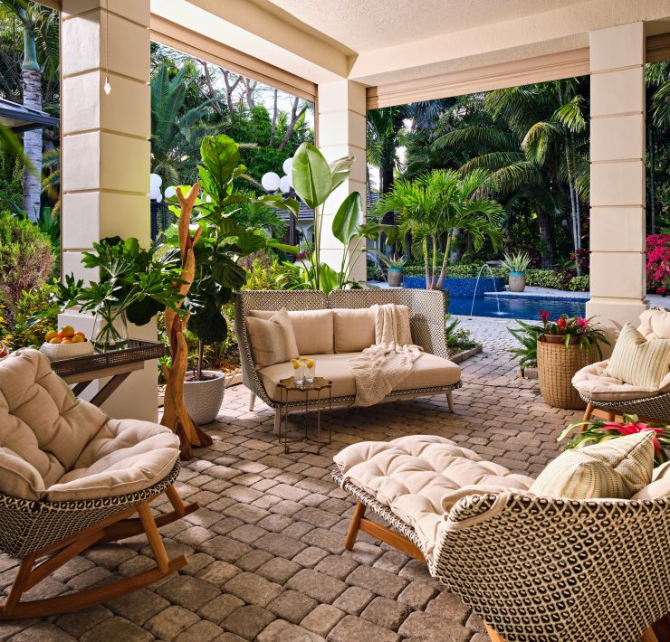 Covered patio with woven seating and tropical landscaping, designed for entertaining in Pinecrest Oasis