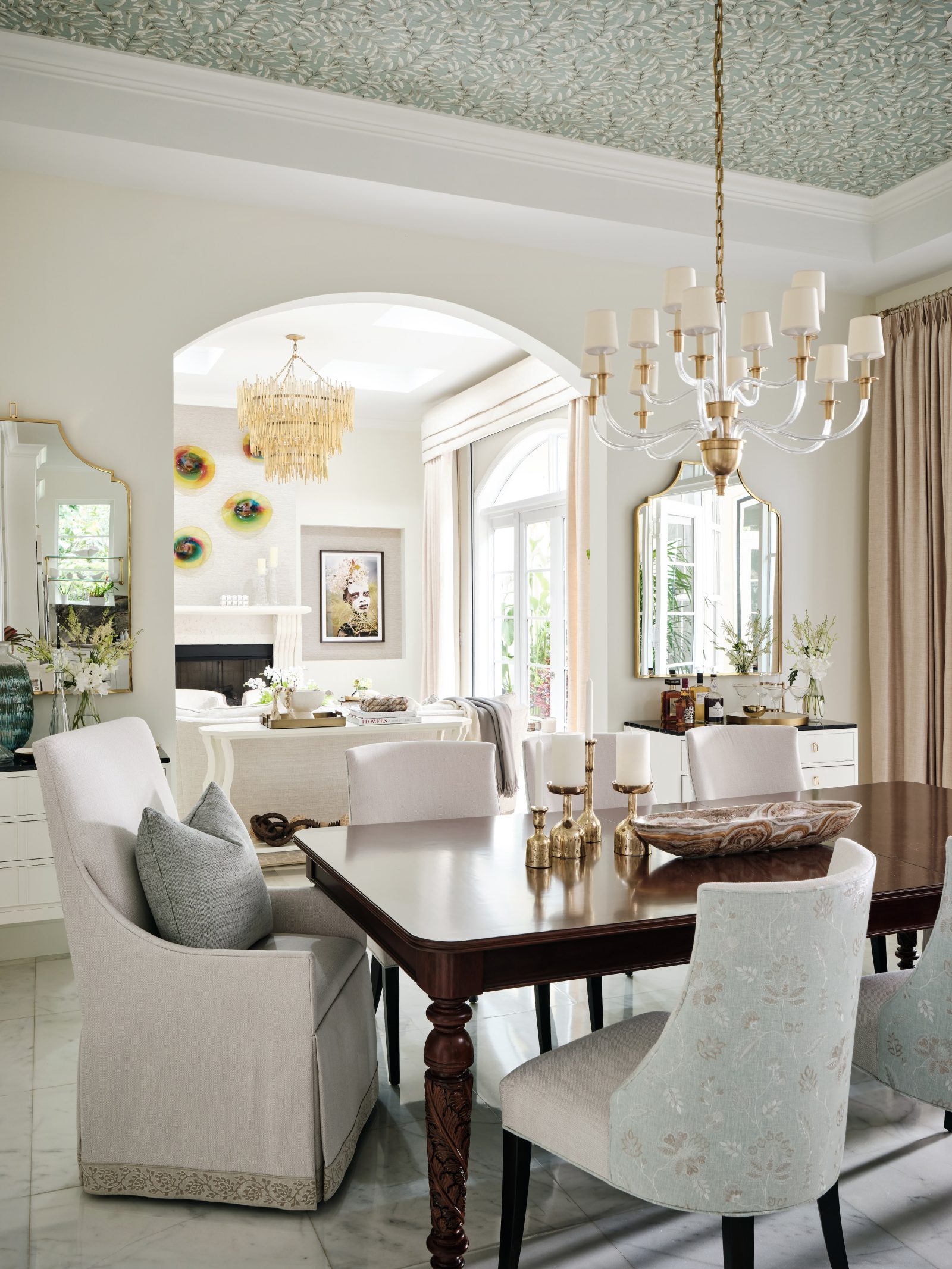Dining room with statement chandelier, coffered ceiling, and neutral tones designed by Maritza Capiro.