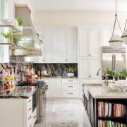Modern white kitchen with marble backsplash, pendant lighting, and open shelving design.