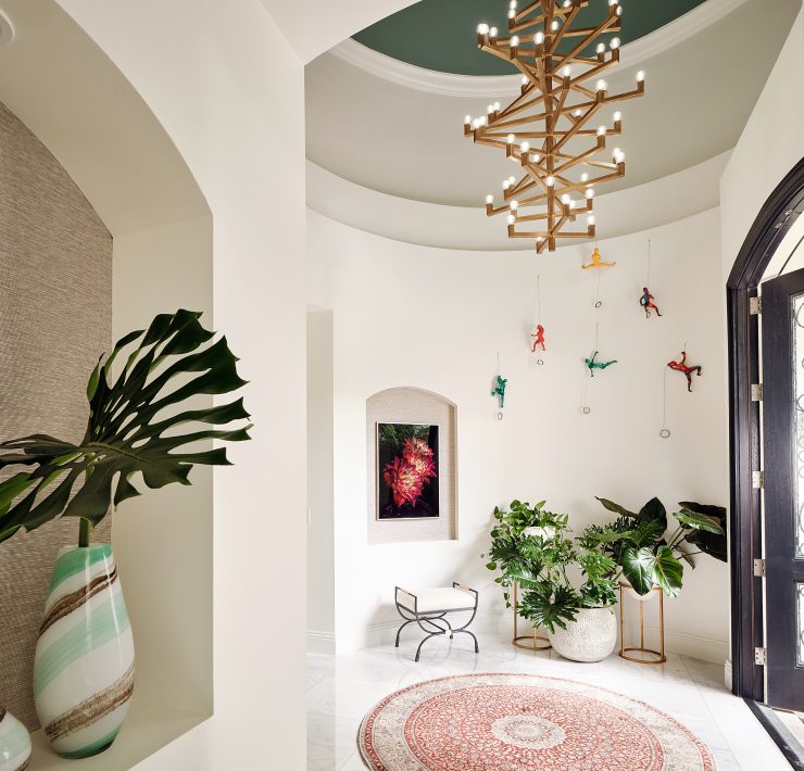 “Elegant foyer with sculptural chandelier, marble floors, and arched entry designed by Maritza Capiro