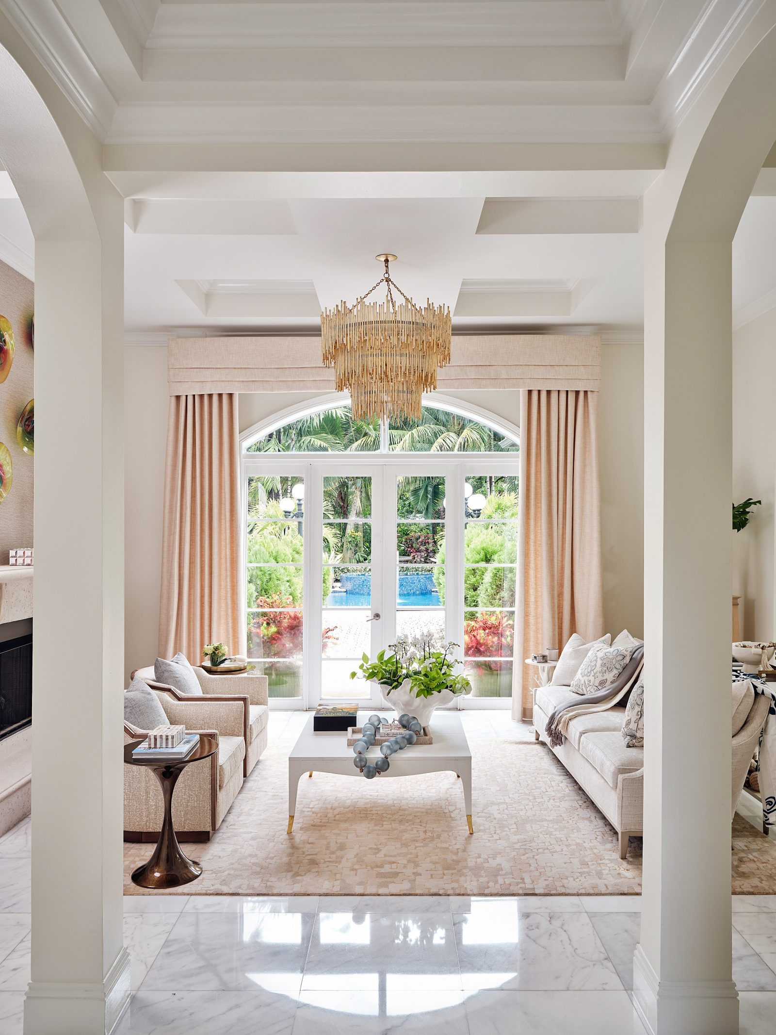 Sophisticated living room with neutral palette, French doors, and chandelier by Maritza Capiro.