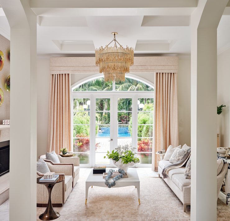 Sophisticated living room with neutral palette, French doors, and chandelier by Maritza Capiro.