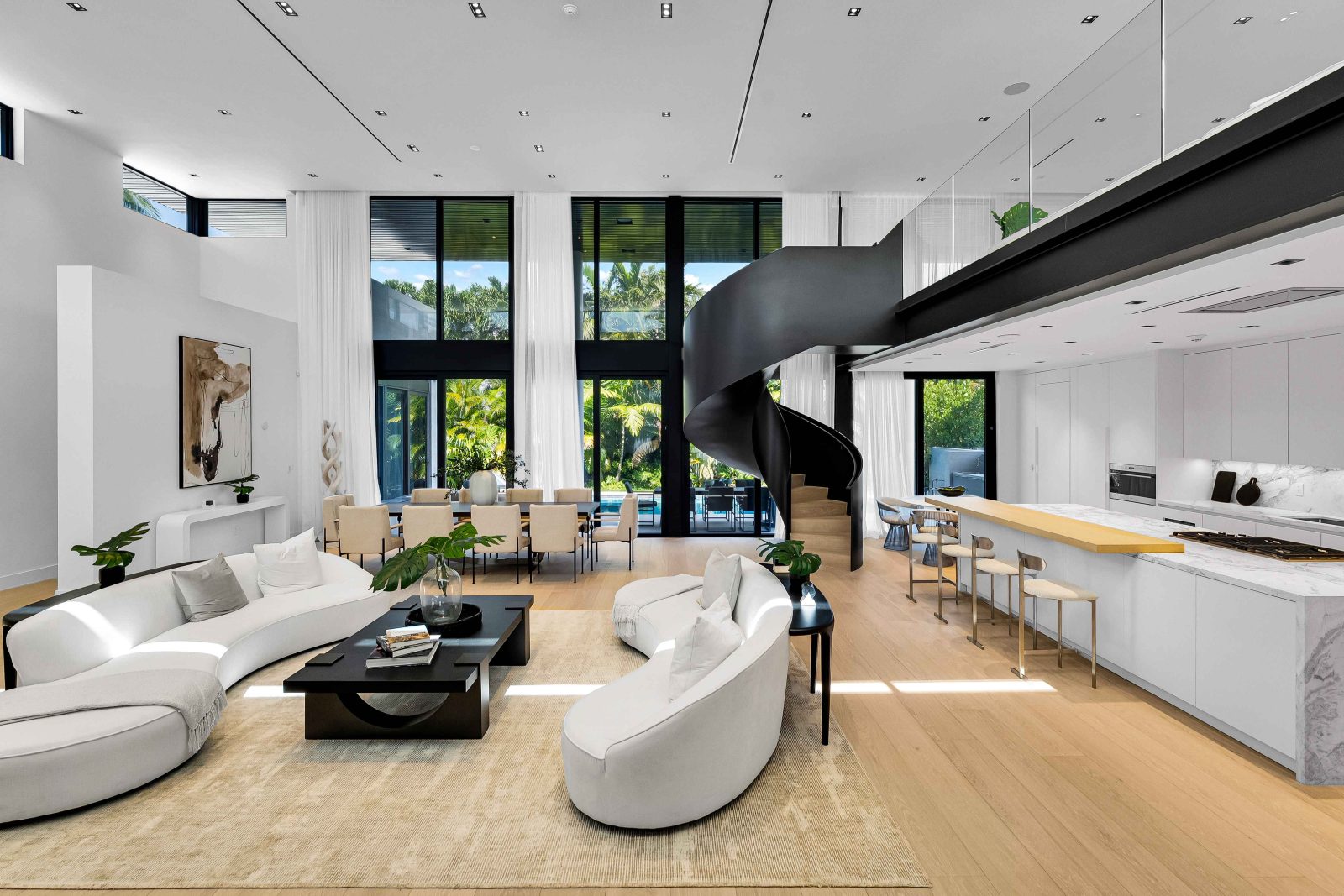 Elegant open-concept living and dining area featuring a sculptural circular staircase and natural light inside the Golden Beach modern estate.