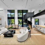 Elegant open-concept living and dining area featuring a sculptural circular staircase and natural light inside the Golden Beach modern estate.