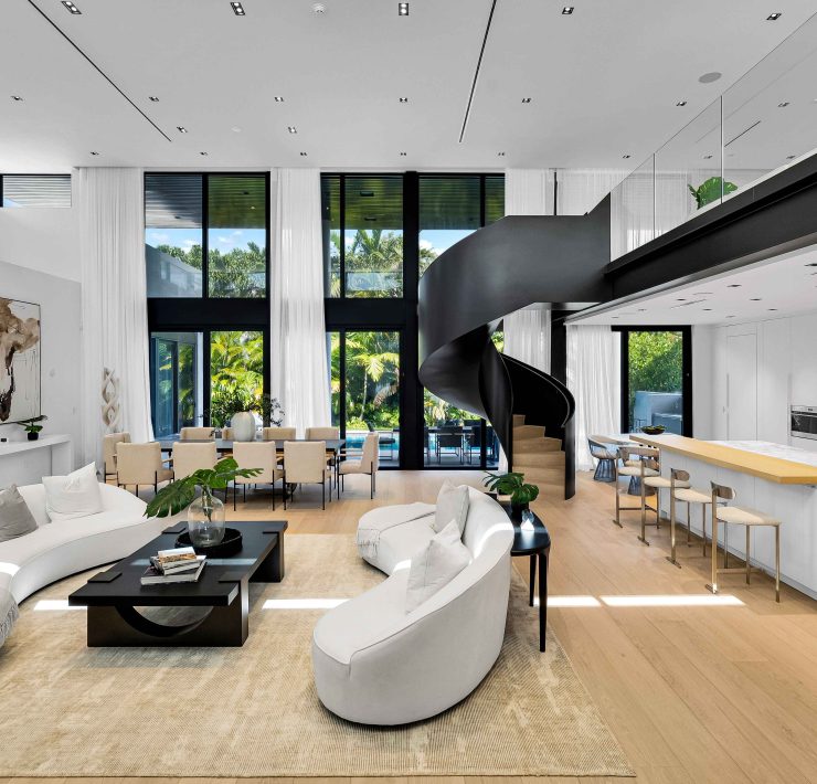 Elegant open-concept living and dining area featuring a sculptural circular staircase and natural light inside the Golden Beach modern estate.