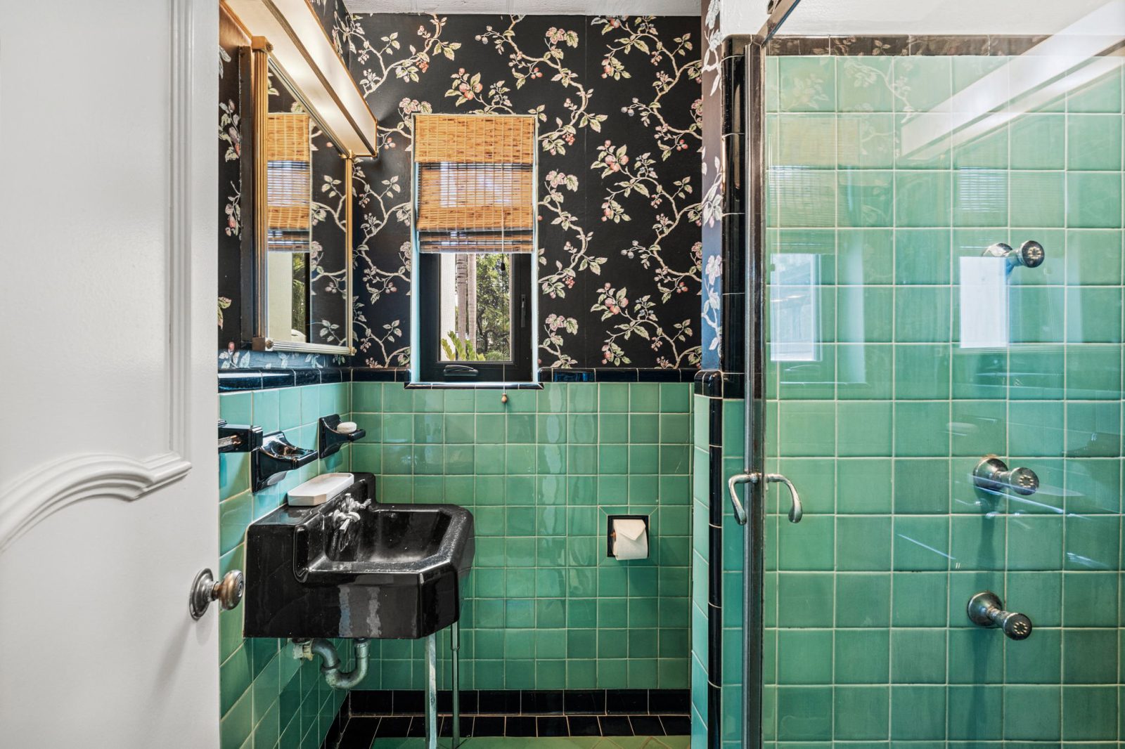 Vintage bathroom with green Art Deco tiles and black fixtures inside the Belle Meade tropical Deco residence.