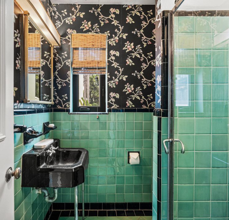 Vintage bathroom with green Art Deco tiles and black fixtures inside the Belle Meade tropical Deco residence.