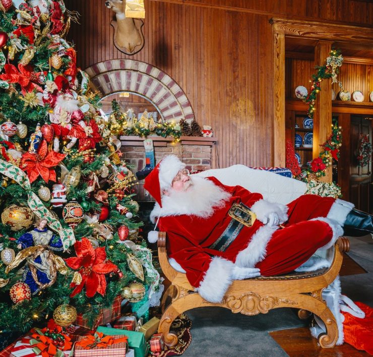 Santa Claus posing beside a decorated Christmas tree inside the Historic Stranahan House Museum in Fort Lauderdale during the Cookies with Santa holiday event.