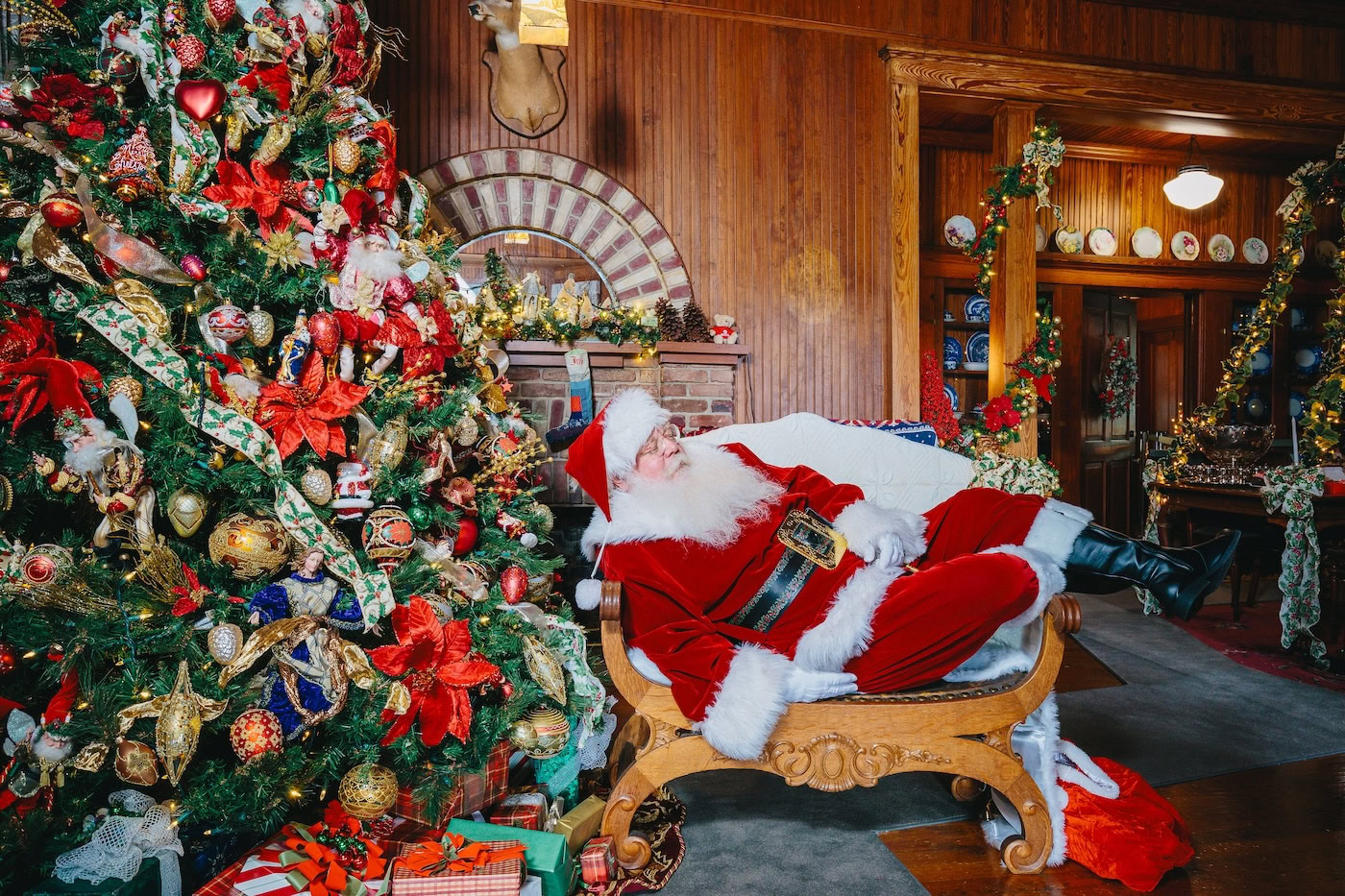 Santa Claus posing beside a decorated Christmas tree inside the Historic Stranahan House Museum in Fort Lauderdale during the Cookies with Santa holiday event.