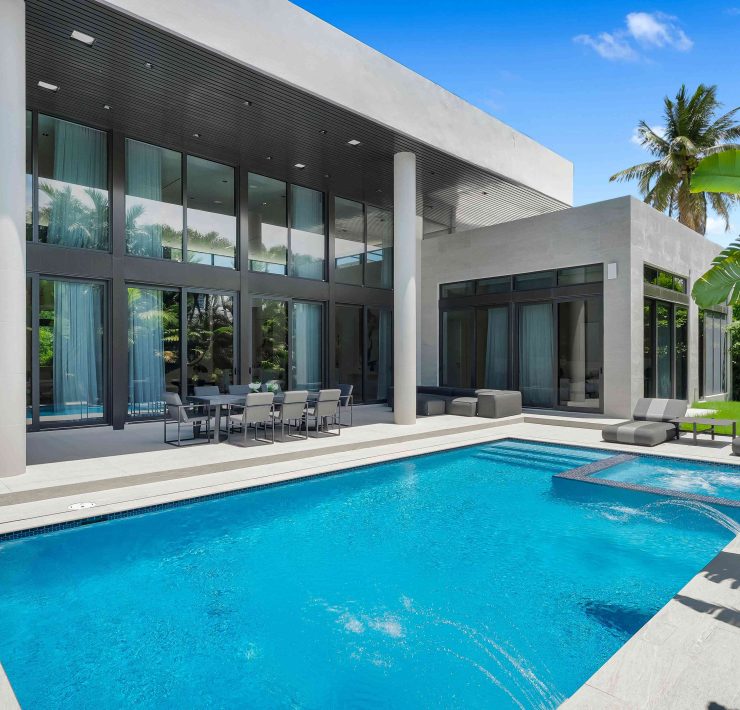 Modern outdoor pool with jacuzzi, terrace seating, and tropical landscaping at a luxury home in Golden Beach, Florida.