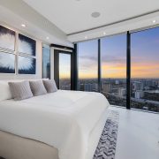 Elegant master bedroom at Porsche Design Tower Penthouse 4405 showcasing floor-to-ceiling glass and panoramic sunset views over Miami.