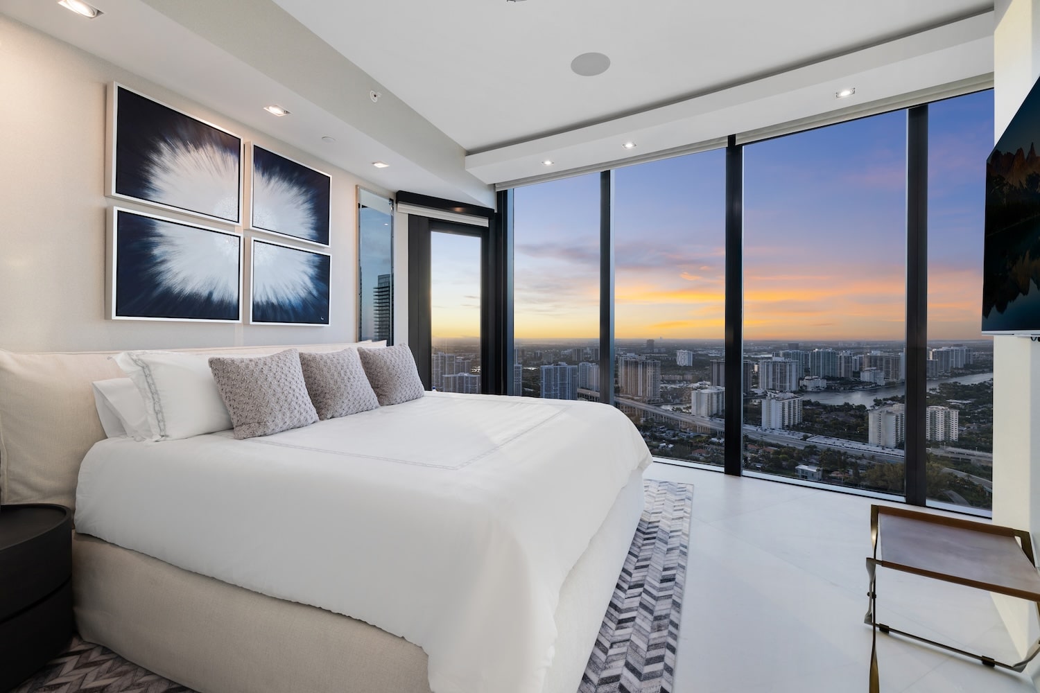 Elegant master bedroom at Porsche Design Tower Penthouse 4405 showcasing floor-to-ceiling glass and panoramic sunset views over Miami.