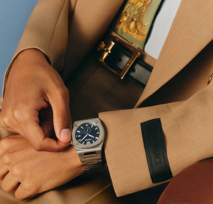 Versace FW25 blue dial timepiece paired with a beige tailored suit, reflecting modern sophistication.