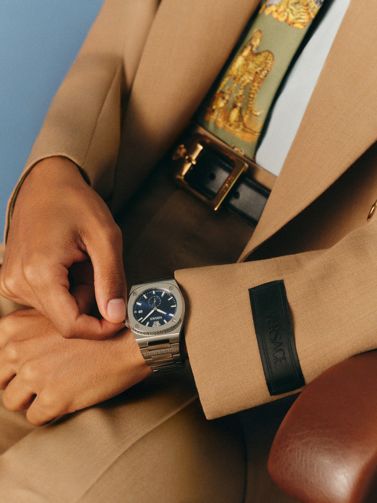 Versace FW25 blue dial timepiece paired with a beige tailored suit, reflecting modern sophistication.
