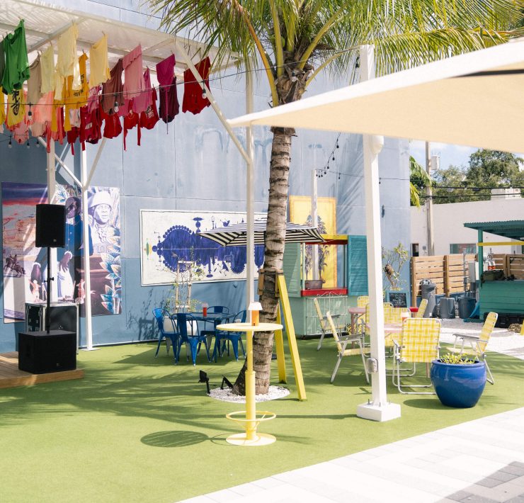 Outdoor courtyard at Lakou Miami in Little Haiti, featuring colorful seating, art installations, and a lively tropical ambiance.