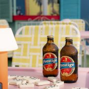 Prestige Haitian beer bottles on a colorful table at Lakou Miami, celebrating Haitian culture and community in Little Haiti.