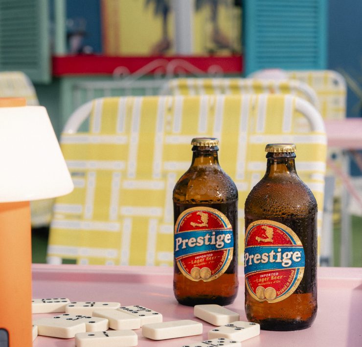 Prestige Haitian beer bottles on a colorful table at Lakou Miami, celebrating Haitian culture and community in Little Haiti.