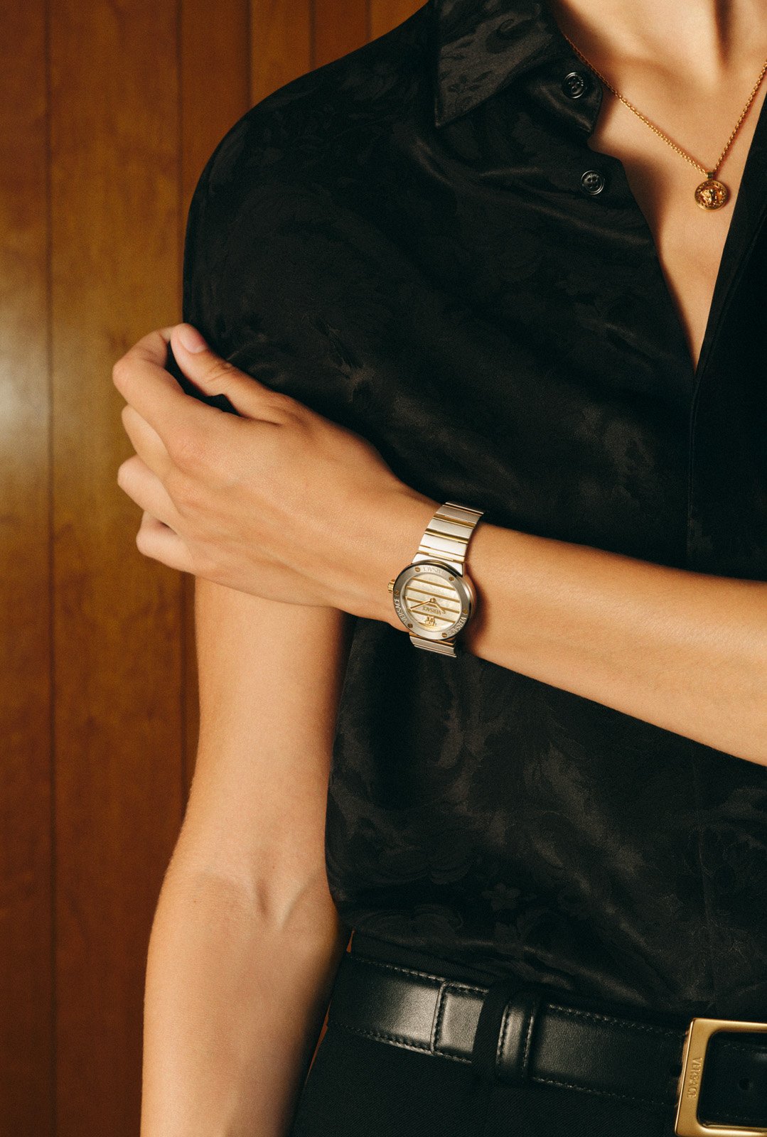 Versace FW25 silver timepiece worn with a black silk shirt, capturing understated elegance.