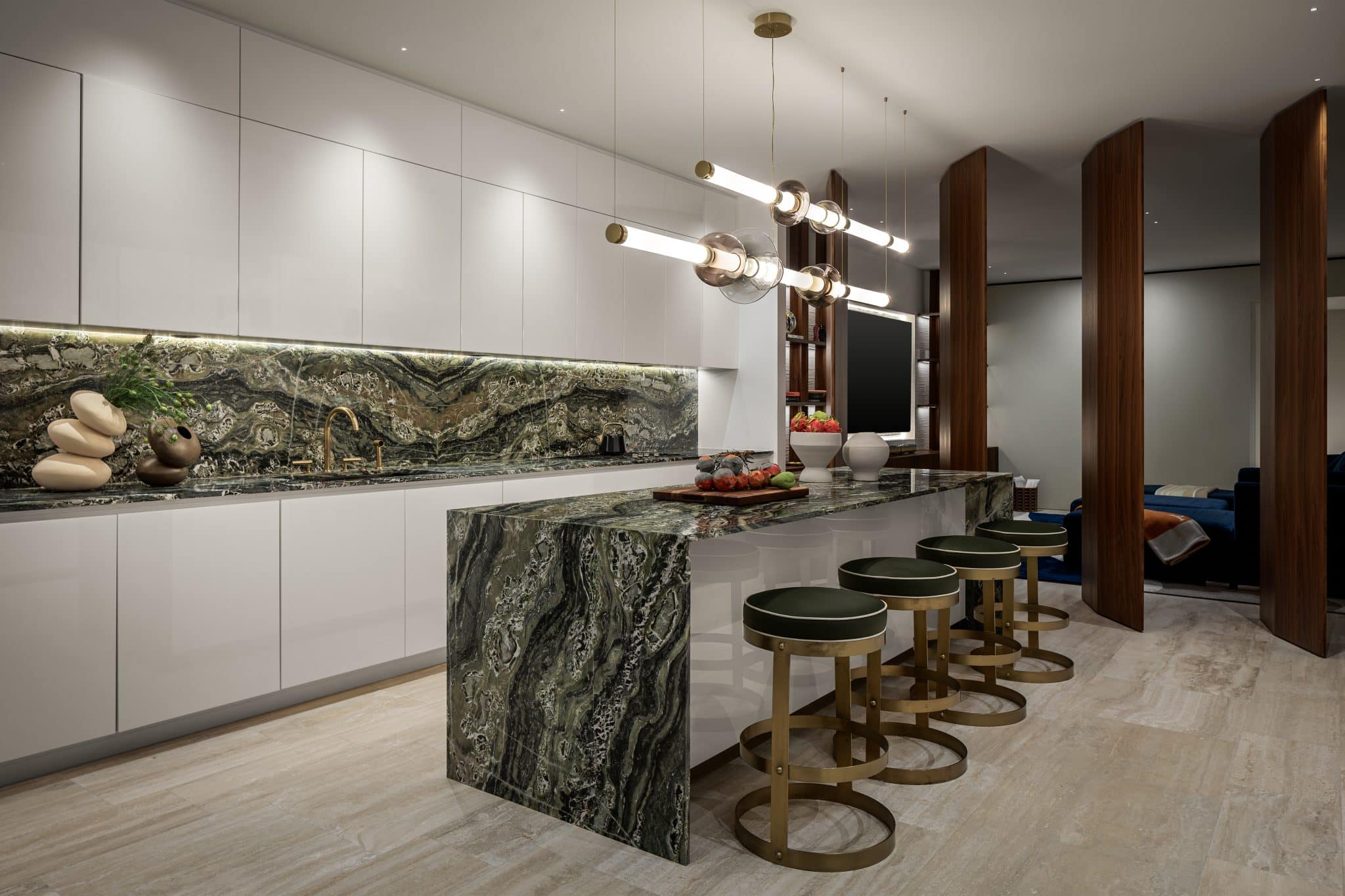 Custom millwork columns inspired by airplane wings separating kitchen and media room with bronze accent shelves